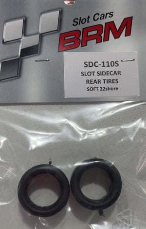 A pair of black rear tires for Slot Cars SDC-110S, sealed in a clear plastic bag with a branded silver and red header card, placed on a light gray surface.